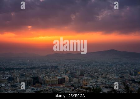 Ein atemberaubender Panoramablick auf Athen bei Sonnenuntergang vom Lycabettus-Hügel. Das Stadtbild erstreckt sich zum Horizont hin, beleuchtet von warmen Goldtönen und d Stockfoto