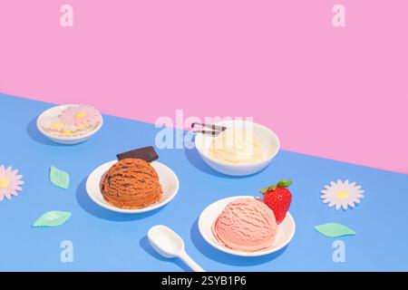 Drei Schalen Eis auf einem rosa und blauen Hintergrund, dekoriert mit einem Schokoladenstück, Vanillebohnen und einer frischen Erdbeere. Stockfoto