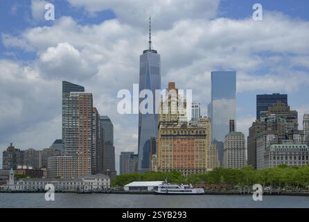 Manhattans Skyline zeigt bemerkenswerte Sehenswürdigkeiten wie das hoch aufragende One World Trade Center, flankiert von verschiedenen Hochhäusern. Diese Aussicht vom Wasser aus Stockfoto
