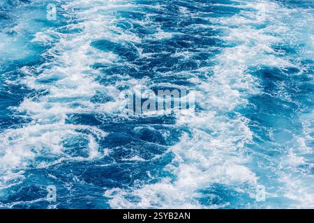Turbulente Meereswellen mit Schaum und Wellen in tiefblauem Wasser. Die Bewegung fängt die rohe Kraft des Ozeans ein. Stockfoto