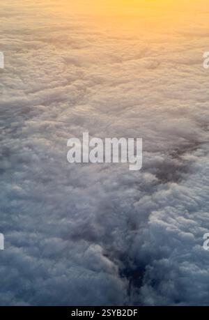Von oben aufgenommen, zeigt dieses Bild eine atemberaubende Decke flauschiger Wolken, die von einem warmen Sonnenaufgang beleuchtet werden und einen ruhigen und atemberaubenden Blick erzeugen Stockfoto