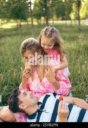 Junge Eltern mit ihrer kleinen Tochter auf einem Picknick im Park im Sommer. Gemeinsame Familienzeit Stockfoto