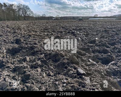 Frisch gepflügtes Feld im Frühjahr, Traktor mit Pflug im Hintergrund, Deutschland, Europa Stockfoto