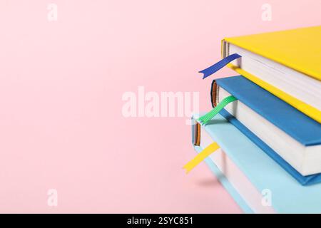 Bücher mit Lesezeichen auf rosafarbenem Hintergrund, Großaufnahme. Leerzeichen für Text Stockfoto