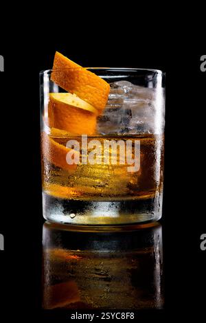 Altmodischer Cocktail mit Eis, garniert mit einer spiralförmigen Orangenschale, auf einem dunklen, stimmungsvollen Hintergrund. Premium-Drink für Luxusbar oder Cocktailmenü Stockfoto
