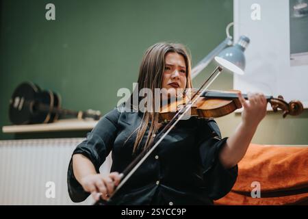 Junge Frau, die mit Leidenschaft Geige spielt, in einem Innenbereich Stockfoto
