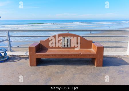 Oceanside, Kalifornien - 26. Dezember 2024: Bequeme Bank für Jerry Stapp, mit Blick auf die Meereswellen am Oceanside mit klarem Himmel Stockfoto