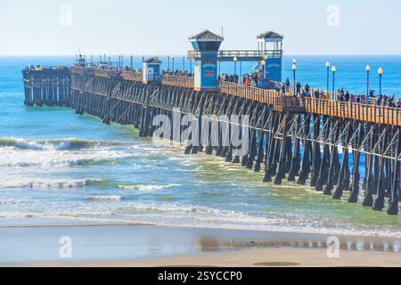 Oceanside, Kalifornien - 27. Dezember 2024: Oceanside Pier voller Besucher unter klarem Himmel und ruhigen Meereswellen. Stockfoto