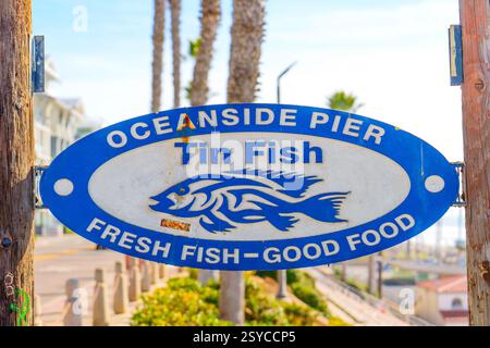 Oceanside, Kalifornien - 27. Dezember 2024: Schild für Tin Fish am Oceanside Pier mit frischem Fisch und Palmen. Stockfoto