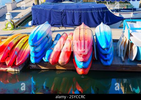 Oceanside, Kalifornien - 27. Dezember 2024: Eine Reihe von gestapelten bunten Kajaks auf einem hölzernen Dock am Yachthafen außerhalb der Saison in Oceanside, Kalifornien. Stockfoto