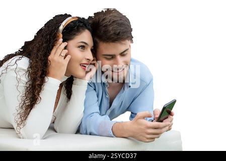 Fröhliches junges Paar auf Matratze mit Gadgets Stockfoto