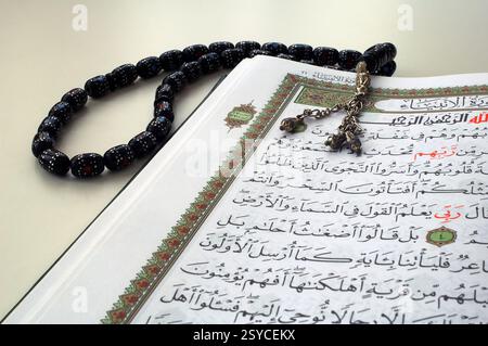 Eine offene Kopie des heiligen Textes des Islam Qur'an umwandelte auch den Koran oder Koran mit schwarzen Misbaha-Gebetsperlen, die oft von Muslimen für die Tasbih, die Gebetsrezitation, den Dhikr und zur Verherrlichung Allahs verwendet werden Stockfoto