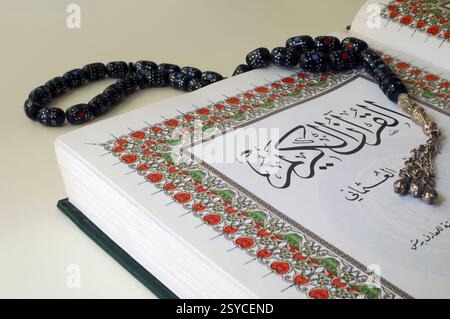 Eine offene Kopie des heiligen Textes des Islam Qur'an umwandelte auch den Koran oder Koran mit schwarzen Misbaha-Gebetsperlen, die oft von Muslimen für die Tasbih, die Gebetsrezitation, den Dhikr und zur Verherrlichung Allahs verwendet werden Stockfoto