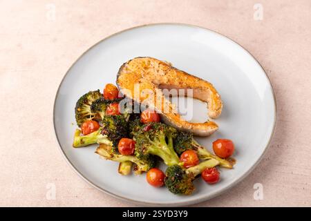 Gebratenes Lachssteak (Forelle) mit gebackenem Brokkoli und Kirschtomaten. Traditionelle Hausmannskost. Selektiver Fokus, Nahaufnahme. Stockfoto