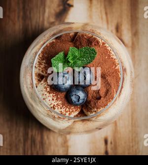 Klassisches italienisches Tiramisu-Dessert im Glas mit frischer Minze und Heidelbeeren. Stockfoto