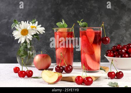 Herbstvitaminglühwein mit Apfelscheiben und Minze. Apfelwein, Saft oder Fruchtgetränk im Glas auf einem sonnigen Tisch, Diät- und Gewichtsreduktion-Konzept. App Stockfoto