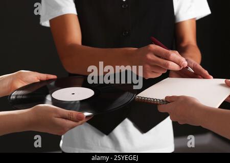 Sängerin signiert Autogramm in Notizbuch auf schwarzem Hintergrund, Großaufnahme Stockfoto