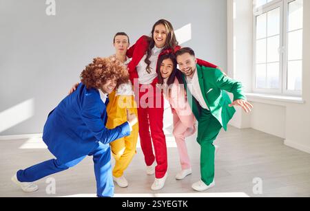 Porträt einer fröhlichen Tanzgruppe in stilvollen, farbenfrohen Anzügen, die Momente des echten Spaßes in der Tanzhalle teilen. Stockfoto