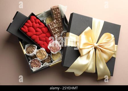 Verschiedene köstliche Schokoladenbonbons in Box auf beigem Hintergrund, Blick von oben Stockfoto