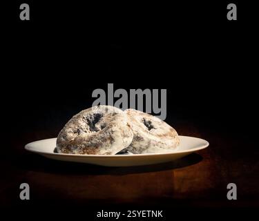 Ein Nahbild von Donuts in Puderform auf einer weißen Platte mit dunklem Hintergrund, die ein Gefühl von heimeliger Nostalgie und Süße weckt. Stockfoto
