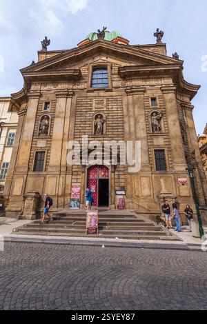 Eine barocke Kirche mit einer symmetrischen Fassade mit Statuen, Bogenöffnungen und einer markanten grünen Kuppel befindet sich auf einem Stadtplatz Stockfoto