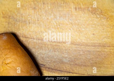 Ein goldbrauner Brotlaib wird auf ein rustikales Holzbrett gelegt. Die warme, einladende Textur der Kruste und die Körnung des Holzes schaffen eine gemütliche Küche Stockfoto