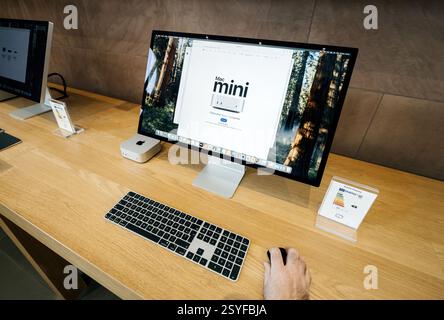 Paris, Frankreich - 18. Februar 2025: Ein Display zeigt einen Mac Mini neben einer Apple-Tastatur und -Maus, und ein Studio Display-Monitor zeigt die Mac's Stockfoto