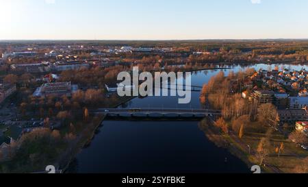 Ein atemberaubender Blick aus der Vogelperspektive auf Karlstad, Schweden, mit gewundenen Flüssen, Brücken und goldenem Sonnenuntergangslicht, das sich auf dem Wasser reflektiert, schafft eine friedliche und malerische skandinavische Landschaft. Stockfoto