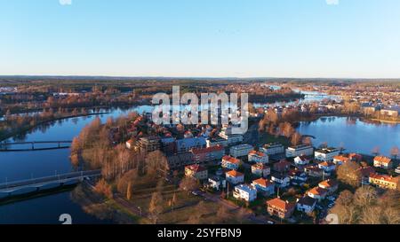 Ein atemberaubender Blick aus der Vogelperspektive auf Karlstad, Schweden, mit Flüssen, Brücken und bezaubernden Häusern mit rotem Dach, die in warmes Sonnenuntergangslicht getaucht sind und eine friedliche und malerische skandinavische Landschaft schaffen. Stockfoto