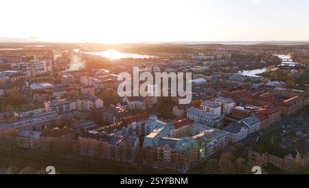 Ein atemberaubender Blick aus der Luft auf Karlstad, Schweden, während Sonnenuntergang, mit historischer Architektur, einem Kirchturm, und goldenes Licht reflektiert auf dem Fluss. Stockfoto