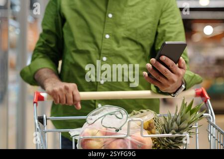 Mann mit Smartphone im Supermarkt Stockfoto