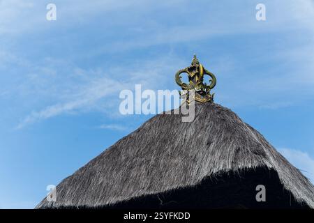 Traditionelles balinesisches Hausdach aus Zuckerpalmenfaser oder Ijuk in Bahasa. Mit geschnitztem Stein oben. Isoliert vom blauen Himmel Stockfoto