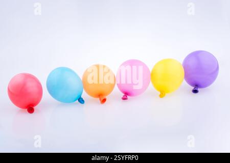Bunte kleine Luftballons in Linie auf weißem Hintergrund Stockfoto
