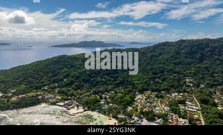 Bewaldete Hügel überblicken ferne Inseln über dem blauen Ozean. La Digue, Seychellen. Stockfoto