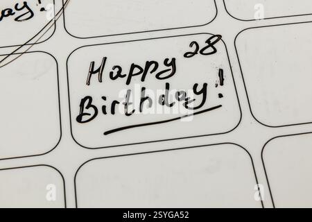 Dunkle Tinte kratzt über die Datumsbox eines Kalenders und feiert einen 28. Geburtstag. Die fröhliche Botschaft vermittelt Freude und Glück für diesen besonderen Anlass. Stockfoto