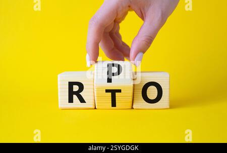 RPO vs. RTO-Symbol. Geschäftsmann-Hand dreht Holzwürfel und ändert das Wort RTO in RPO. Schöner gelber Hintergrund. Geschäftskonzept. Kopierbereich Stockfoto