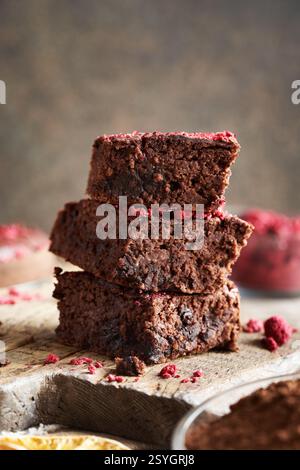 Ein Stapel hausgemachter glutenfreier Brownies aus roten Kidneybohnen, Haferflocken, Schokolade und gefriergetrockneten Himbeeren auf einem Holztisch Stockfoto
