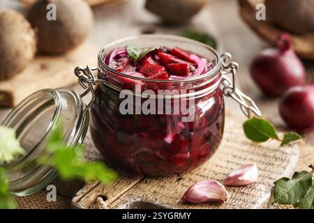 Zubereitung von fermentiertem Rübenkwass in einem Glas mit frischer Rote Bete, Zwiebeln, Knoblauch und Gewürzen Stockfoto