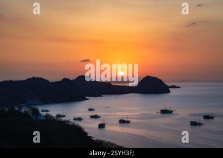 Ein atemberaubender Sonnenuntergang färbt den Himmel über ruhigen Meeren voller Fischerboote, Yachten und Silhouetteninseln, die eine friedliche Küstenszene schaffen, die Stockfoto