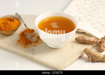 Aromatischer Kurkuma-Tee, Pulver und Rhizome auf weißem Tisch, Nahaufnahme Stockfoto
