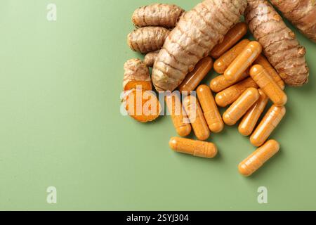 Kurkuma-Rhizome und -Kapseln auf grünem Hintergrund, flache Lagen. Leerzeichen für Text Stockfoto