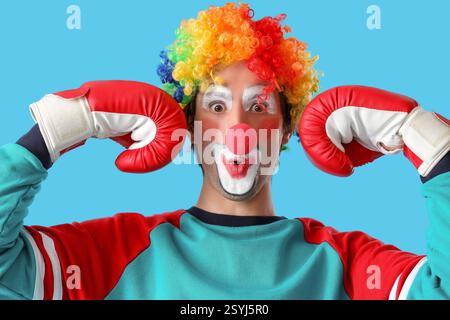Porträt eines überraschten Clowns mit Boxhandschuhen auf blauem Hintergrund. Aprilfeier zum Narrentag Stockfoto
