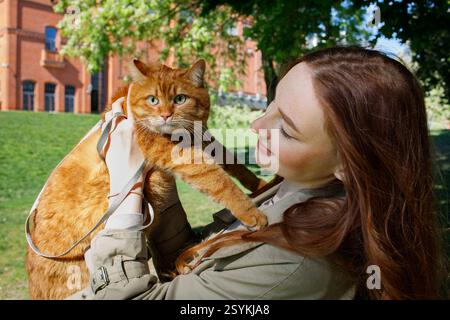 Ingwermädchen mit Ingwerkatze an der Leine im Park Stockfoto