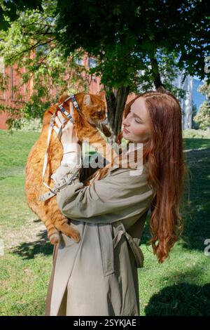 Ginger Girl geht mit einer Ingwerkatze an der Leine im Park Stockfoto