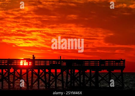Isle Of Palms, Usa. März 2025. Eine Person, die vom Sonnenaufgang über dem Atlantischen Ozean geschildert wird, beobachtet vom Isle of Palms Pier am Front Beach, 1. März 2025 in Isle of Palms, South Carolina. Eine allmähliche Erwärmung bis in die 70er Jahre wird sich nach einem harten Winter im Tiefland fortsetzen. Quelle: Richard Ellis/Richard Ellis/Alamy Live News Stockfoto