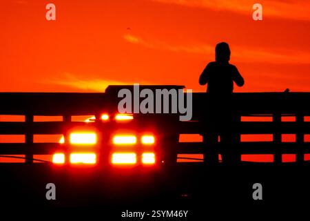 Isle Of Palms, Usa. März 2025. Eine Person, die vom Sonnenaufgang über dem Atlantischen Ozean geschildert wird, beobachtet vom Isle of Palms Pier am Front Beach, 1. März 2025 in Isle of Palms, South Carolina. Eine allmähliche Erwärmung bis in die 70er Jahre wird sich nach einem harten Winter im Tiefland fortsetzen. Quelle: Richard Ellis/Richard Ellis/Alamy Live News Stockfoto