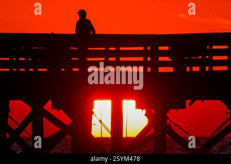 Isle Of Palms, Usa. März 2025. Eine Person, die Silhouetten hatte, aber der Sonnenaufgang über dem Atlantik beobachtet vom Isle of Palms Pier am Front Beach, 1. März 2025 in Isle of Palms, South Carolina. Eine allmähliche Erwärmung bis in die 70er Jahre wird sich nach einem harten Winter im Tiefland fortsetzen. Quelle: Richard Ellis/Richard Ellis/Alamy Live News Stockfoto