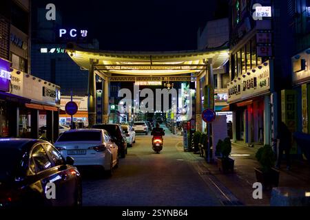 Buyeo County, Südkorea - 27. Mai 2021: Eine belebte Straße in der Innenstadt von Buyeo, beleuchtet von Neonlichtern und traditionellen Torbauten, mit Geschäften Stockfoto