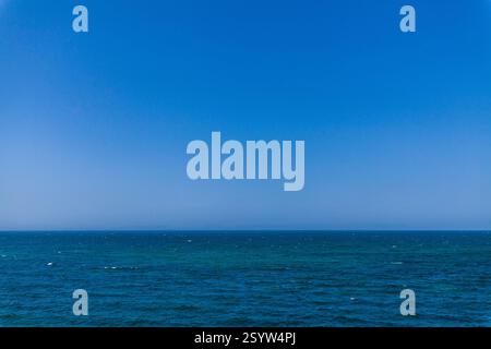 Weite Weite des tiefblauen Wassers trifft auf einen klaren blauen Himmel und schafft eine minimalistische und beruhigende Komposition Stockfoto
