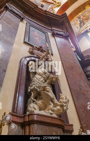 Eine Statue, die einen Ritter zu Pferd zeigt, der einen Drachen tötet, in einer Nische in einem Innenraum mit einem Gemälde darüber und dekorativen Elementen positioniert Stockfoto